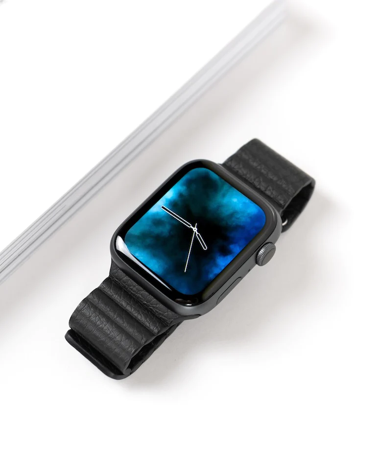 skeuomorphism: still life photo of an Apple Watch with only the hands of a traditional clock visible on its digital screen.