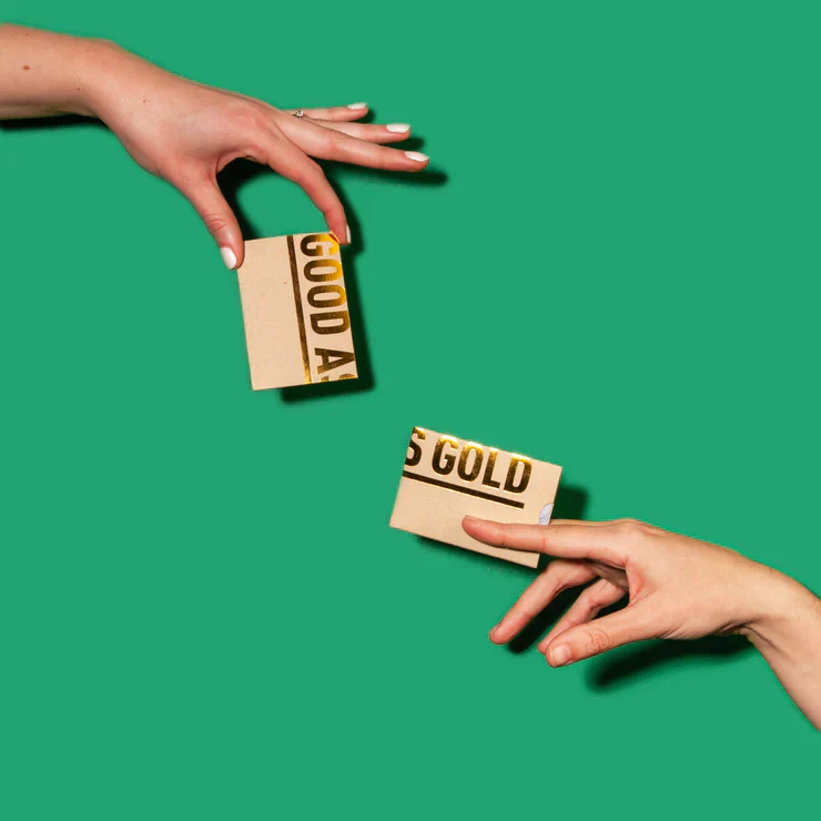 Two hands holding gift cards against a green background